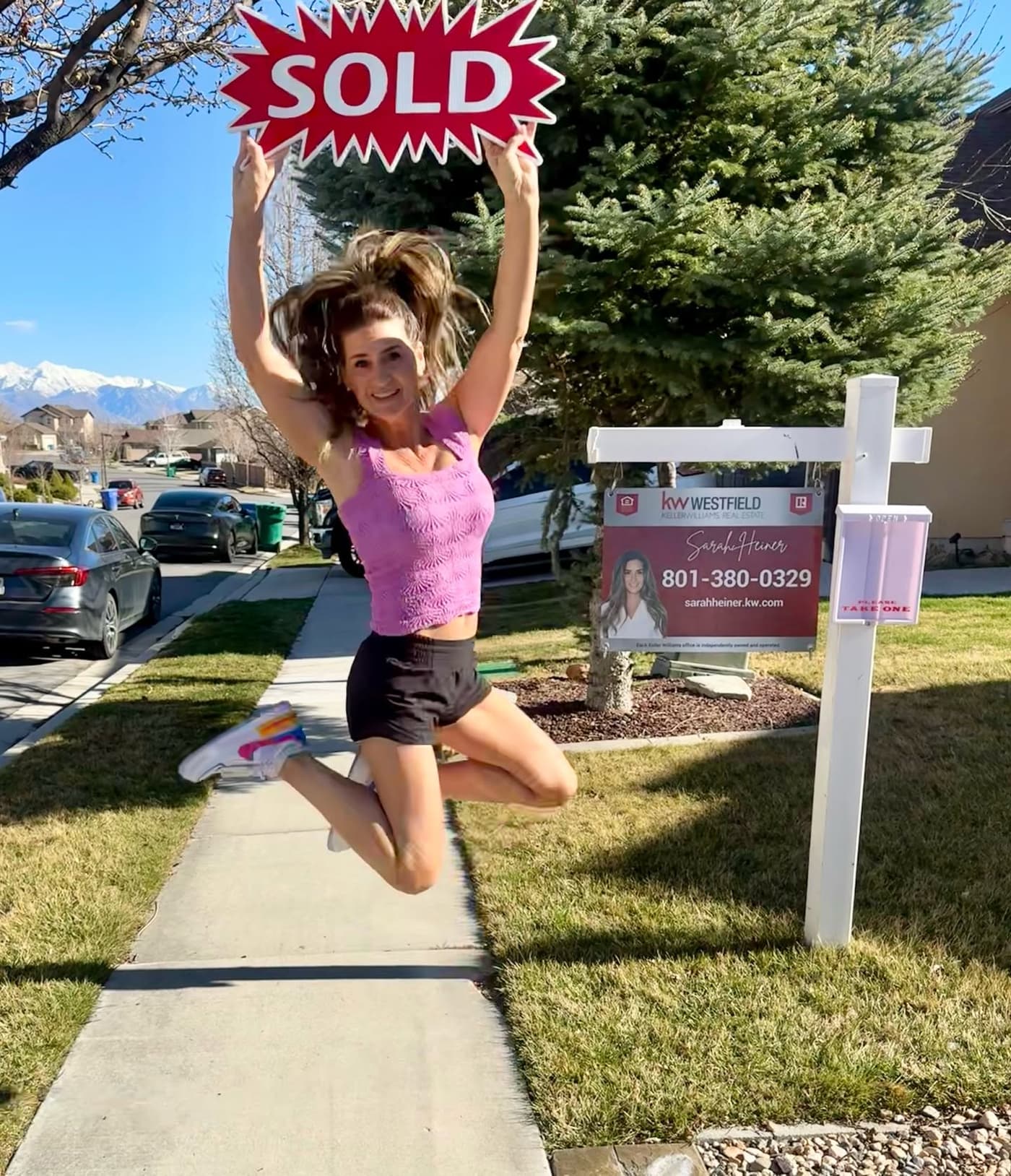 Sarah Heiner celebrating in front of a home with a Sold sign