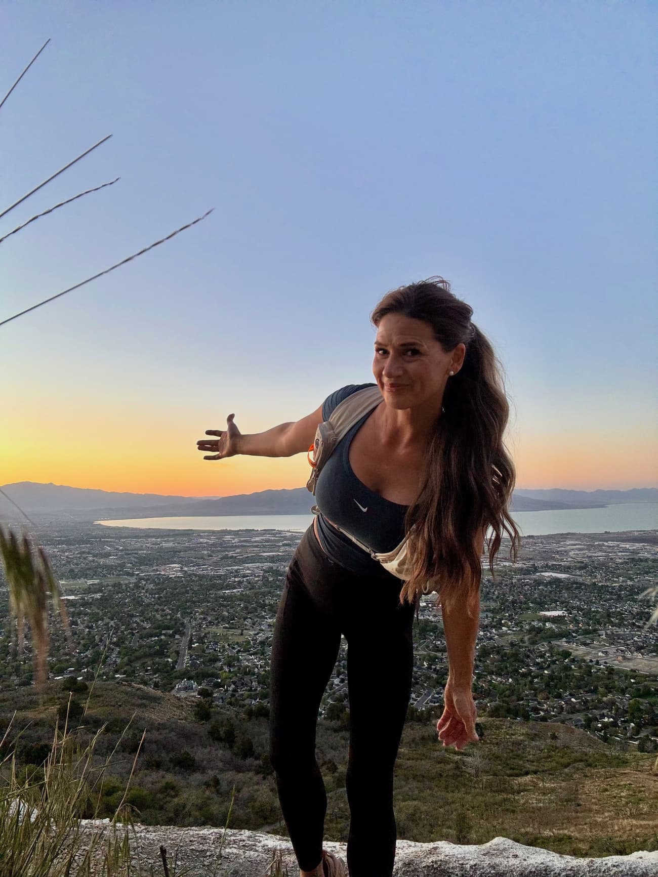 Sarah Heiner on a mountain summit above a Utah valley at sunset
